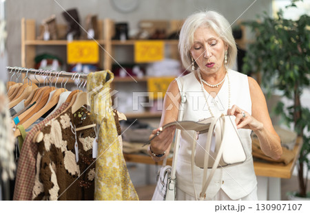 Elderly woman choosing a fashionable handbag in boutique Elderly woman choosing a fashionable handbag in boutique 130907107
