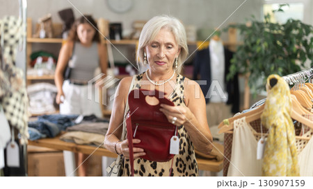 Elderly woman choosing a fashionable handbag in boutique Elderly woman choosing a fashionable handbag in boutique 130907159
