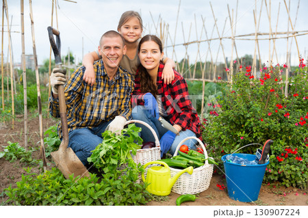 Couple of gardeners with child posing with harvest of vegetables Couple of gardeners with child posing with harvest of vegetables 130907224