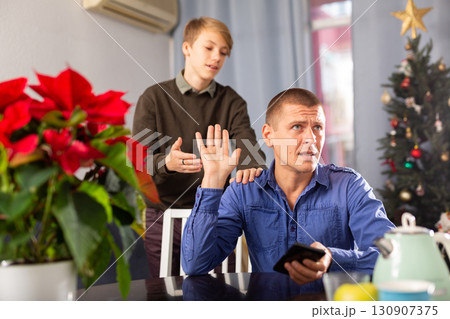 Upset father turned away after quarrel with his teenage son during Christmas celebration closeup Upset father turned away after quarrel with his teenage son during Christmas celebration closeup 130907375