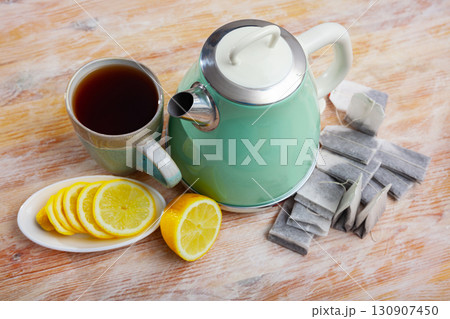 New teapot on table with cup of black tea and sliced lemon New teapot on table with cup of black tea and sliced lemon 130907450