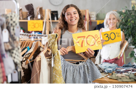 Two positive women holding sale banner in clothing store Two positive women holding sale banner in clothing store 130907474