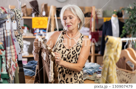 Elderly woman chooses cardigan in clothing store Elderly woman chooses cardigan in clothing store 130907479