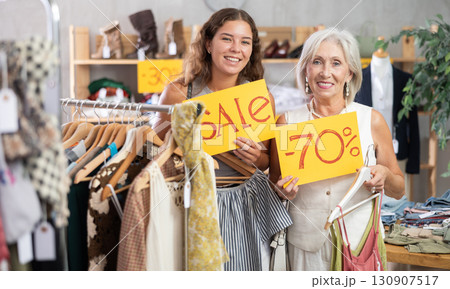 Two positive women holding sale banner in clothing store 130907517