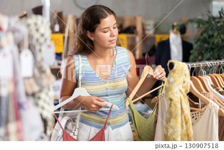 Young woman choosing summer clothes in store Young woman choosing summer clothes in store 130907518