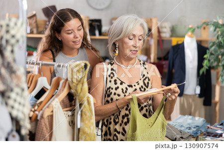 Elderly and young women choosing summer clothes in store 130907574
