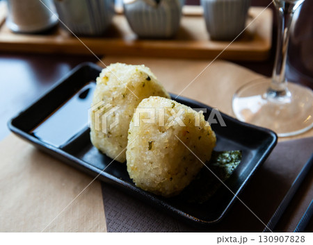Fresh Japanese triangular onigiri with rice at black plate 130907828