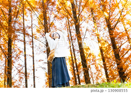 紅葉した森の中で腕を伸ばしている女性　ライフスタイルイメージ 130908555
