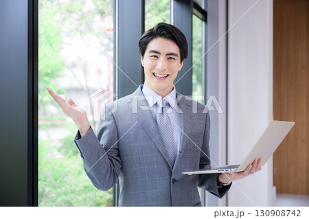 パソコンを持つスーツの男性 コンサルタント、リクルートなど転職のイメージ　笑顔でカメラ目線でオススメ 130908742