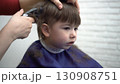 three-year-old sitting in barber chair watching the mirror during a haircut 130908751