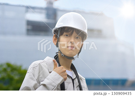 工事現場でタブレットを見る作業服の若いビジネスマン 130909435