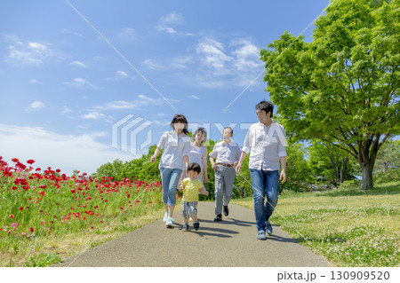 ポピーの咲く公園を歩く3世代家族 130909520