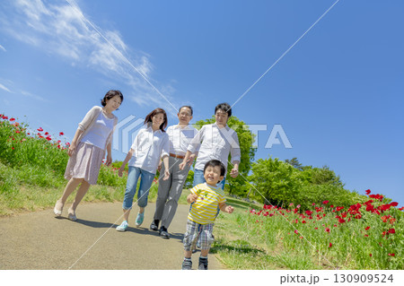 ポピーの咲く公園を歩く3世代家族 130909524