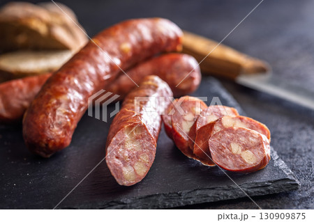 Smoked sliced sausages on cutting board on black table. 130909875