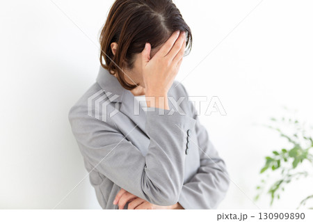 頭を抱えて悩むグレーのスーツ姿のミドル女性ビジネスウーマン 130909890