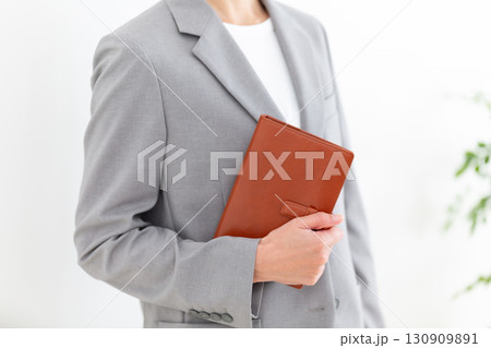 手帳を持つグレーのスーツ姿のミドル女性ビジネスウーマン 手帳を持つグレーのスーツ姿のミドル女性ビジネスウーマン 130909891