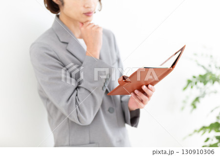 手帳を見るグレーのスーツ姿のミドル女性ビジネスウーマン 130910306