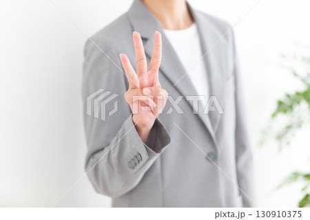 指を3本立てるグレーのスーツ姿のミドル女性ビジネスウーマン 130910375