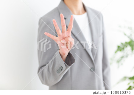 指を4本立てるグレーのスーツ姿のミドル女性ビジネスウーマン 指を4本立てるグレーのスーツ姿のミドル女性ビジネスウーマン 130910376