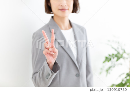 指を2本立てるグレーのスーツ姿のミドル女性ビジネスウーマン 130910780