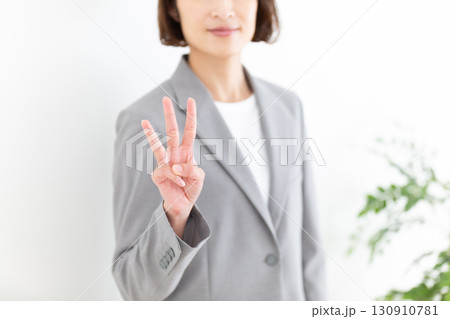 指を3本立てるグレーのスーツ姿のミドル女性ビジネスウーマン 130910781