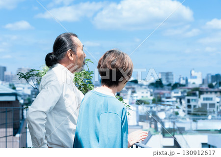 テラスで街を眺めるシニア夫婦 130912617