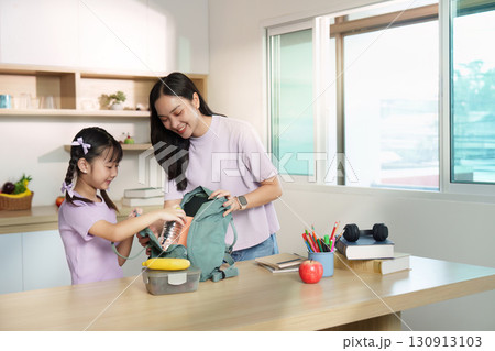 Back to School. Mother helping daughter pack her backpack for school. 130913103