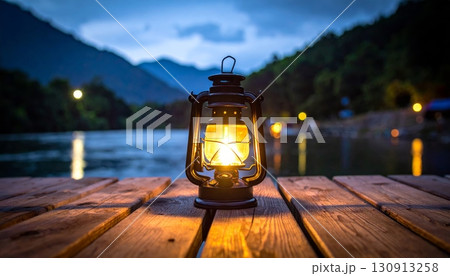 An ancient metal lantern on wooden table side lake An ancient metal lantern on wooden table side lake 130913258