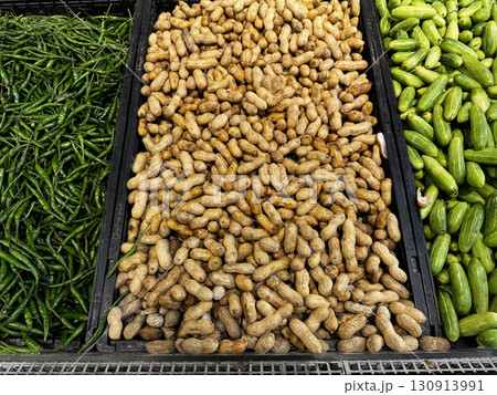 Trays of unshelled peanuts and green vegetables arranged in a market produce section Trays of unshelled peanuts and green vegetables arranged in a market produce section 130913991