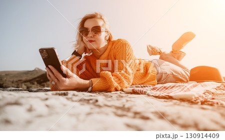 Woman Relaxing on a Hillside, Using Her Phone Woman Relaxing on a Hillside, Using Her Phone 130914409
