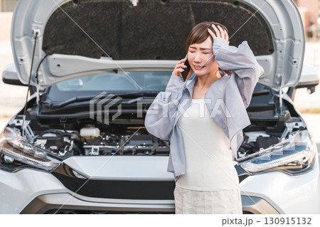 自動車の前でスマホで電話するアジア人女性（ロードサービス・トラブル・レスキュー・困る） 130915132