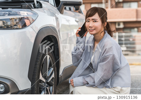 自動車の前でスマホで電話するアジア人女性（ロードサービス・トラブル・レスキュー・困る） 130915136
