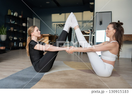 two women hold a partner boat pose on a soft rug, linking hands and extending legs, cultivating serenity and balance during a minimalist home yoga practice two women hold a partner boat pose on a soft rug, linking hands and extending legs, cultivating serenity and balance during a minimalist home yoga practice 130915183