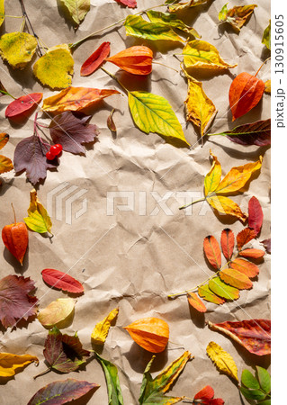 Autumn foliage frame with colorful leaves and physalis on crumpled brown paper with copy space. 130915605