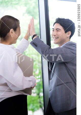 ハイタッチで成功や成果をあげる笑顔のビジネスマン2人 プロジェクトの成功などのポシティブ男女 ハイタッチで成功や成果をあげる笑顔のビジネスマン2人 プロジェクトの成功などのポシティブ男女 130915805