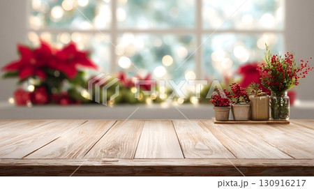 A wooden table displays festive red berries and plants, set against a blurred Christmas window background with glowing lights. 130916217