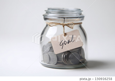 Jar of money collecting coins towards a future goal 130916258