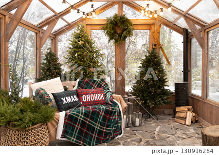 A festive sunroom with a cozy bench, Christmas trees, and holiday decor, and inviting view of a snowy winter wonderland A festive sunroom with a cozy bench, Christmas trees, and holiday decor, and inviting view of a snowy winter wonderland 130916284
