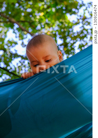 Baby Peeking Over Turquoise Fabric Outdoors 130916474