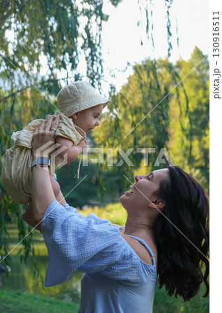 Mother Lifting Baby Outdoors in Sunny Park Mother Lifting Baby Outdoors in Sunny Park 130916511