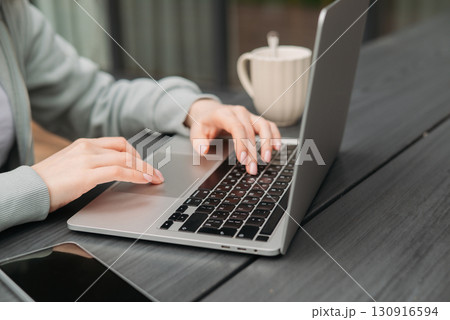A professional woman working on her laptop outdoors. This image captures the modern concept of remote work A professional woman working on her laptop outdoors. This image captures the modern concept of remote work 130916594