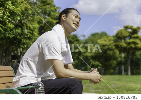 公園のベンチに座って休憩する若い男性 公園のベンチに座って休憩する若い男性 130916785