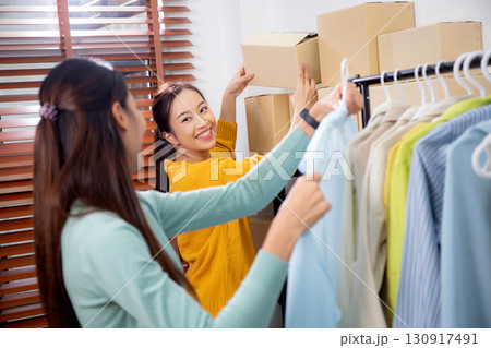 Two young asian woman arranging clothes in store for preparation delivery, seller choice clothes. Two young asian woman arranging clothes in store for preparation delivery, seller choice clothes. 130917491