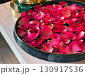 Vibrant rose petal rest on the surface of water in a bowl, creating a calming focal point in a wellness center. Soft light enhances the soothing atmosphere, ideal for meditation. 130917536