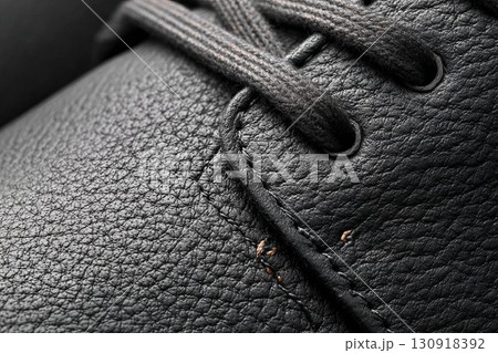 Dark leather shoe with lace-up front. Detailed view of high-quality shoe material. Ideal for elegant fashion or product shoot. 130918392