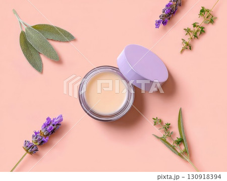 Cream jar with purple lid on peach base. Surrounded by lavender, sage, and thyme, this skincare product feels natural. Perfect for beauty or spa photos. 130918394