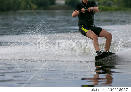 man on wakeboard is wakeboarding on pond 130918637