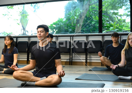 Multi ethnic yoga practitioners sitting cross-legged with eyes closed for mindfulness 130919156