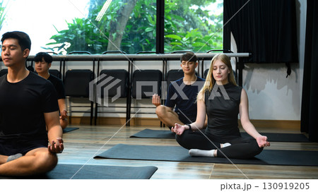 Group of people meditating in lotus position during a yoga class in a studio. Wellness concept Group of people meditating in lotus position during a yoga class in a studio. Wellness concept 130919205