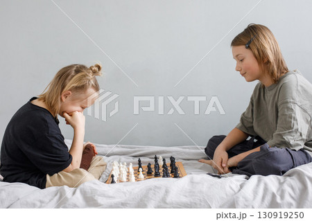 Concentrated clever children with board game having fun. Two cute children playing chess at home 130919250